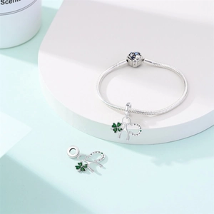 Macro detail of silver horseshoe and green clover charm with Good Luck engraving