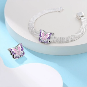 Detail eines silbernen Mesh-Armbands mit rosa und lila Emaille-Schmetterling-Anhängern