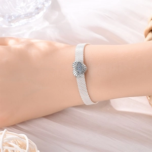 Dettaglio di un bracciale a maglia argento con ciondolo a cuore malocchio sul polso