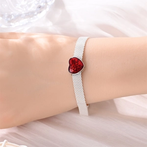 Nahaufnahme eines silbernen Mesh-Armbands mit rotem Herzanhänger und Be Mine Gravur