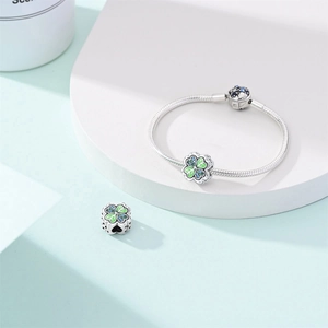 Detail of silver clover charm with green enamel and blue zircons on snake chain