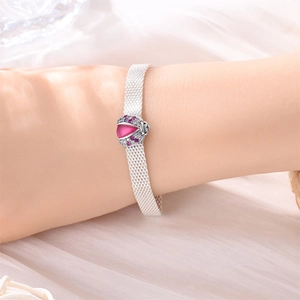 Detail eines Marienkäfer-Anhängers mit rosa Steinen auf einem silbernen Mesh-Armband