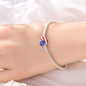 Nahaufnahme eines herzförmigen US-Flaggen-Charms am silbernen Schlangenarmband am Handgelenk