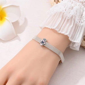 Close-up of a silver mesh bracelet with floral charm on a woman's wrist