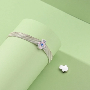 Detail of silver mesh bracelet with Hamsa Hand charm and blue gemstone inlay