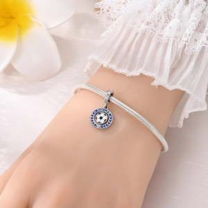 Detalle macro de un charm de fútbol de plata con esmalte azul en una pulsera