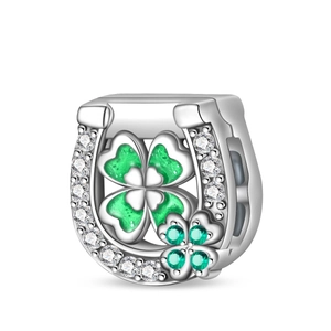 Macro detail of silver horseshoe and green clover charm with sparkling zircon inlay
