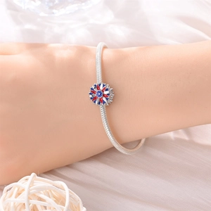 Details des Schlangenkettenarmbands mit rot weiß blau emailliertem Blumenanhänger am Handgelenk