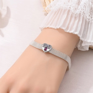 Detailed view of a silver mesh bracelet featuring a vintage heart charm with purple zircon