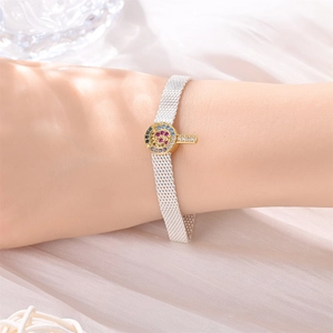 Detailansicht eines gewebten Silberarmbands mit buntem Zirkonia-Anhänger in Goldfassung