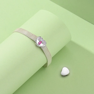 Detailed shot of a silver mesh bracelet with heart clasp and pink gemstone inlay