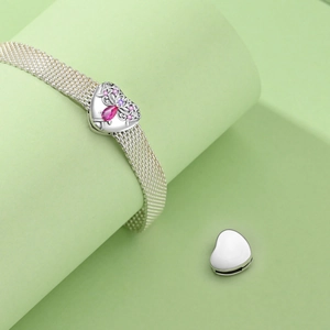 Macro shot of silver mesh bracelet with pink heart charm and gemstone vine detailing