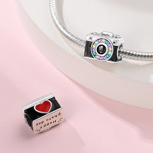 Macro detail of camera charm with colorful stones and Happy Photo Day engraving