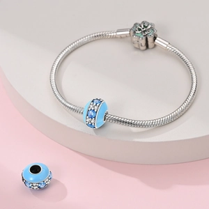 Gros plan d'une breloque macaron en émail bleu sur un bracelet maille serpent avec fermoir