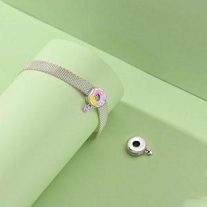 Detail of silver mesh bracelet featuring a colorful donut charm with purple heart pendant
