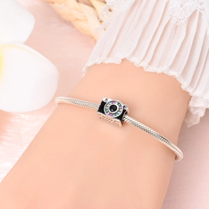 Detailed close-up of camera charm with colorful stones and Happy Photo Day engraving