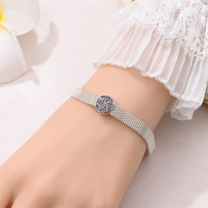 Silver mesh bracelet with purple floral charm on a female wrist for jewelry design