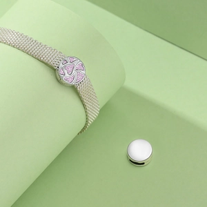Detailed shot of mesh bracelet with pink heart-shaped buckle on geometric backdrop