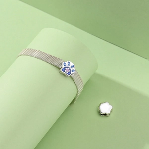 Detailed close-up of a silver mesh bracelet with a colorful jeweled cat paw charm