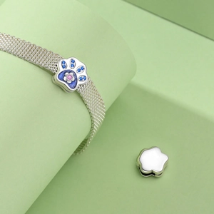 Detail of silver mesh bracelet with blue paw charm featuring floral enamel details