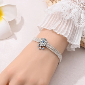 Silver mesh bracelet with snowflake pendant and blue gems worn on wrist in a soft setting