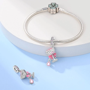 Detail of silver snake chain bracelet with green clover clasp and pink cup charms