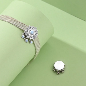 Detail of silver mesh bracelet featuring a sun flower charm and blue star pendants