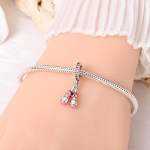 Detailed close-up of a silver charm bracelet featuring pink enamel champagne bottle charms