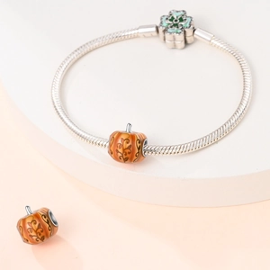 Macro detail of pumpkin charm with orange enamel on a clover clasp silver snake chain