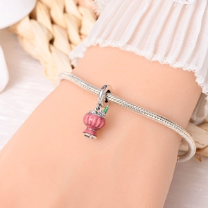 Close-up of pink enamel beer mug charm on a silver snake chain bracelet worn on wrist