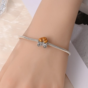 Detailed view of a silver pumpkin carriage charm bead on a snake chain bracelet
