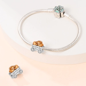 Detail of silver-plated pumpkin carriage charm on a snake chain bracelet with floral clasp