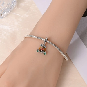 Macro shot of silver pumpkin carriage charm with orange heart stone on a snake chain bracelet