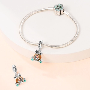 Macro detail of silver pumpkin carriage charm with orange heart stone and HAPPY engraving