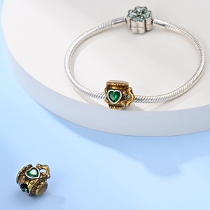 Macro detail of beer mug charm bead in brown enamel with green heart-shaped zircon