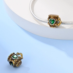 Macro view of vintage bronze barrel charm with heart-shaped green stone for bracelets