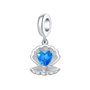 Macro shot of silver shell charm with heart-shaped blue gemstone and micro zircons