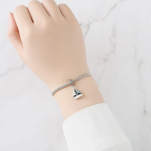 Close-up of a silver sailboat charm with blue enamel on a snake chain bracelet