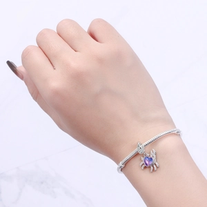 Close-up of a crab charm with a purple heart gemstone on a silver snake chain bracelet