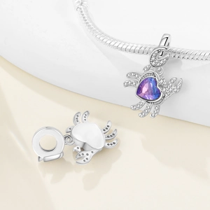 Macro detail of silver crab charm with heart-shaped purple stone and zircon inlay