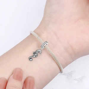 Detailed macro view of a silver seahorse charm pendant worn on a stylish mesh bracelet.