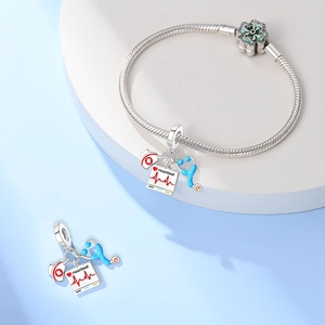 Detail van stethoscoop en verpleegstersmuts bedeltjes aan een zilveren slangenarmband