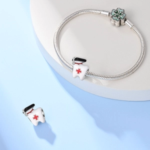 Macro-opname van zilveren slangenarmband met groene bloem en tand met verpleegstersmuts bedels