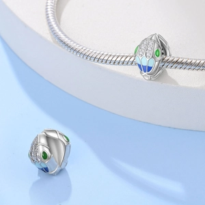 Detail van zilveren slangenbedel met groene emaille ogen op een slangenarmband