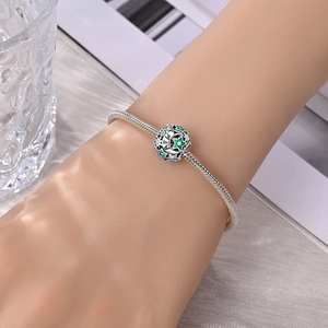 Versilbertes Schlangenarmband mit grünem Mai-Geburtsstein-Sternanhänger am Handgelenk