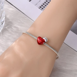 Detailopname van verpleegsterarmband met rood hartje en wit emaille hoedje hanger
