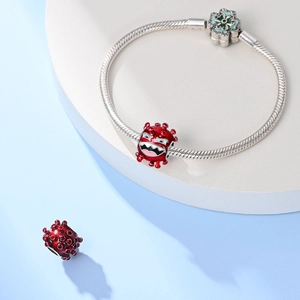 Zilveren slangenarmband met rode monsterbedeltjes en groene emaille bloemluiting detail