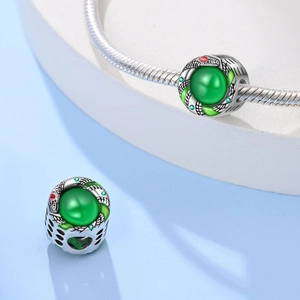 Zilveren slangenbedel met groene edelsteen aan armband, minimalistische uitstraling