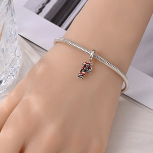 Detail van verzilverde slangenarmband met rood geëmailleerde zuurstok-hanger aan de pols