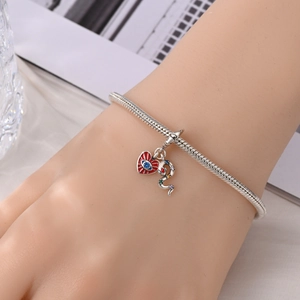 Detail van zilveren slangenarmband met rood emaille hartje en bezette slangenbedel